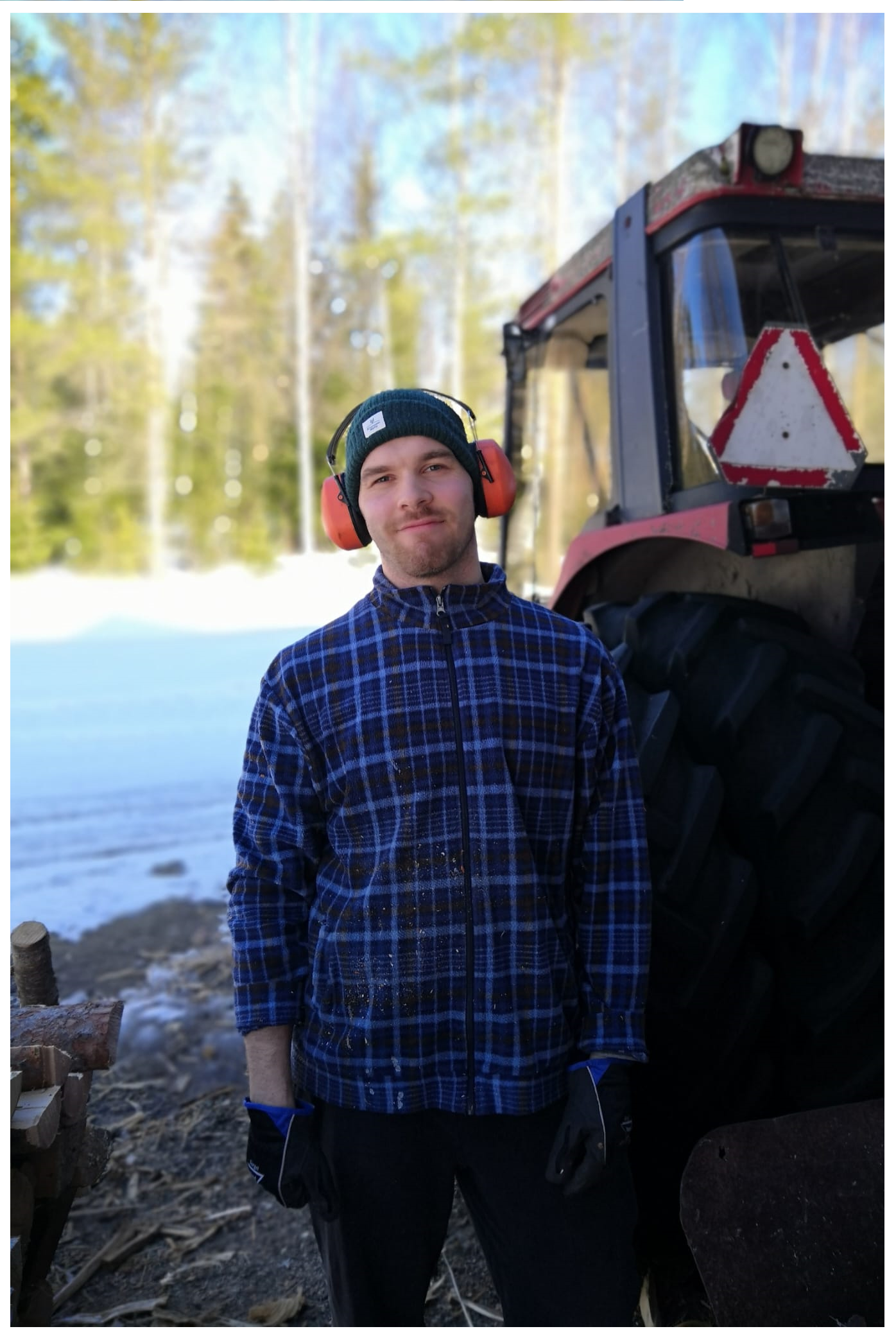 Kuvassa opiskeluhuollon psykologi Petteri Ruuhijärvi ulkona traktorin edessä, kuulokkeet päässään ja katsoo kameraan.