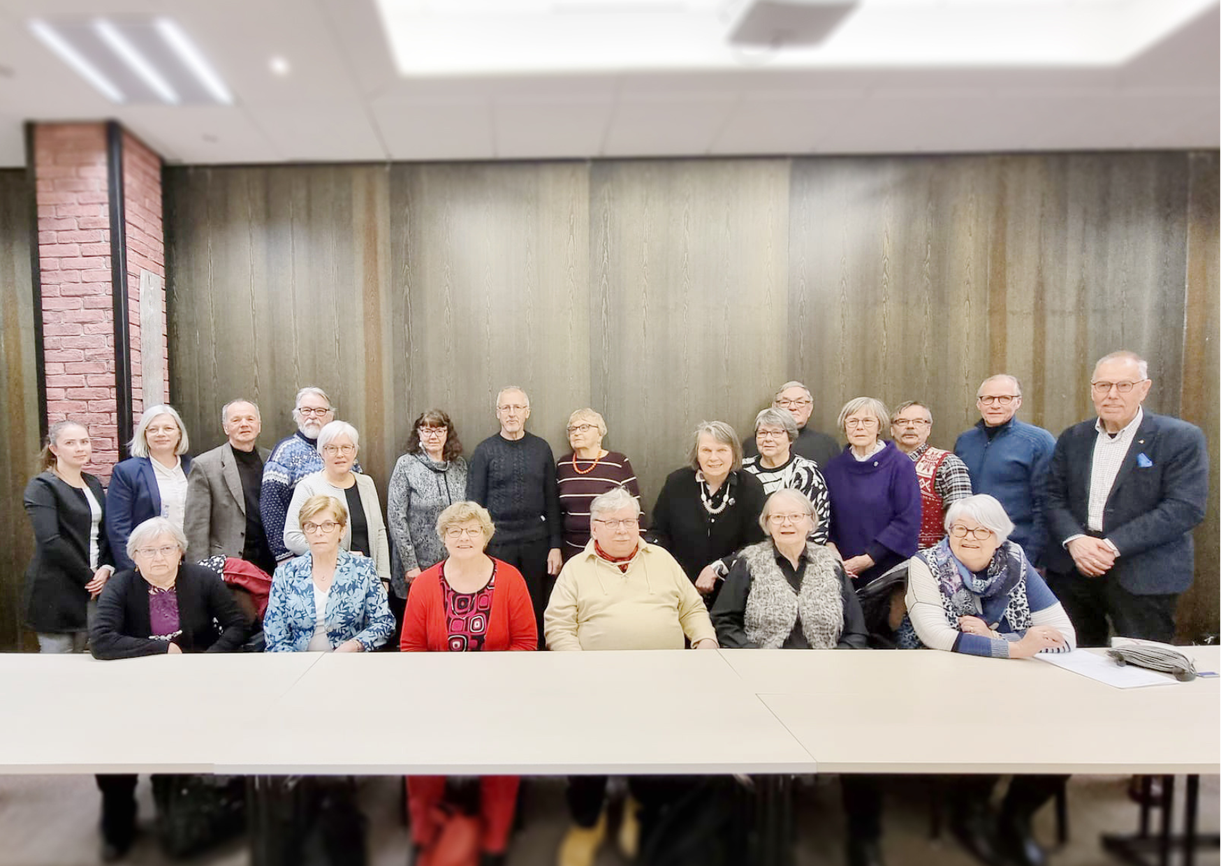 Vanhusneuvoston kaksikymmentäyksi jäsentä ovat kokoontuneet kahteen riviin poseeraamaan kameralle. Kuva on vanhusneuvoston ensimmäisestä kokouksesta.