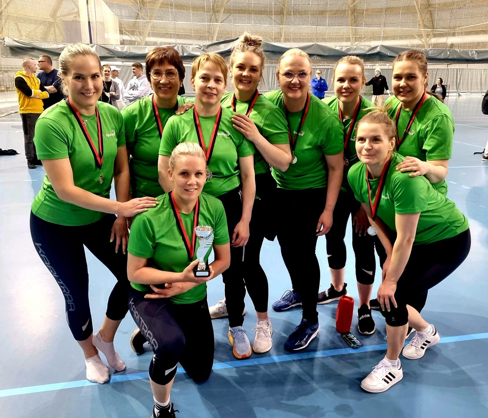 Lapin hyvinvointialueen naisten lentopallojoukkue, 9 vihreäpaitaista naista poseeraa kameraan